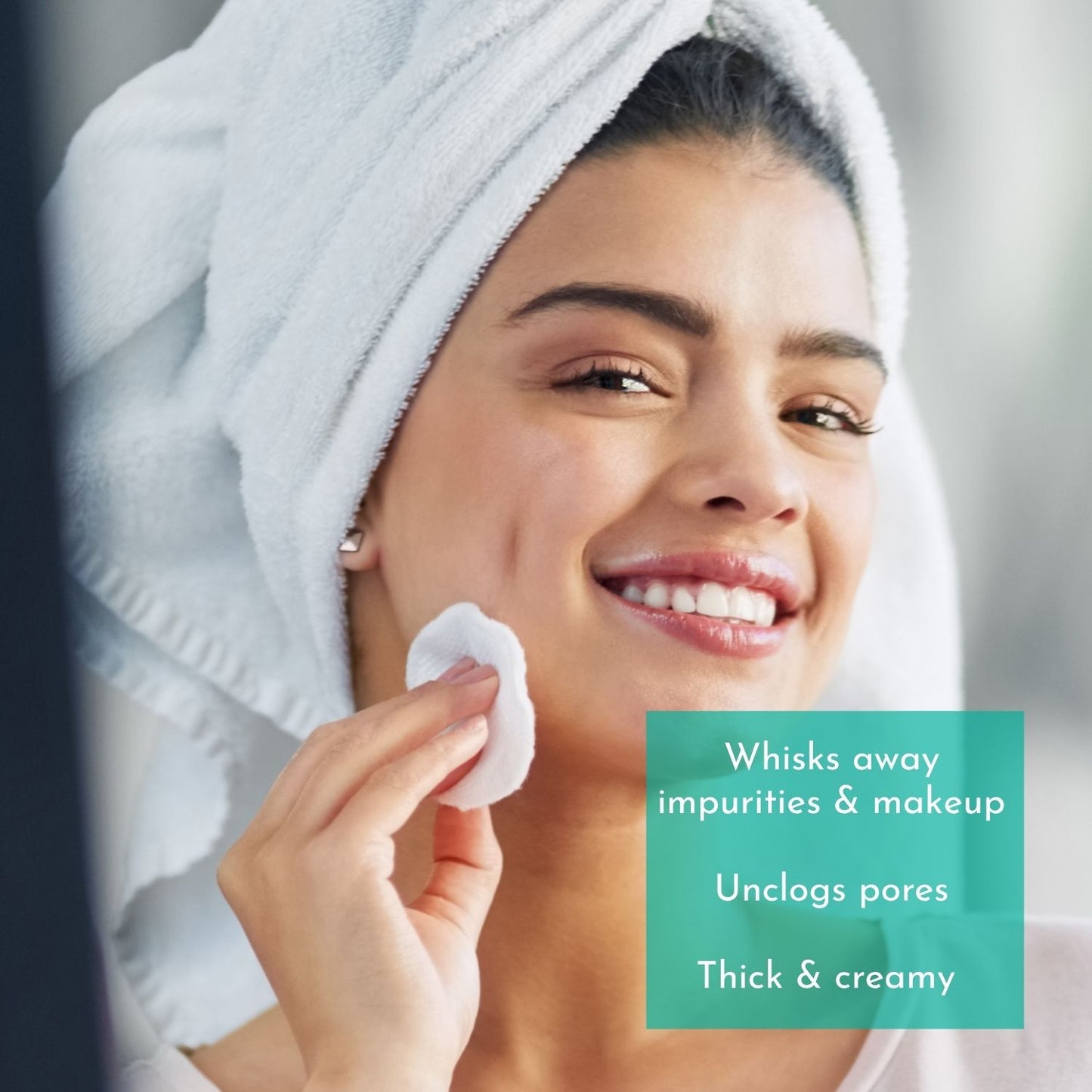 Woman applying a thick, creamy product to her face with a towel on her head.